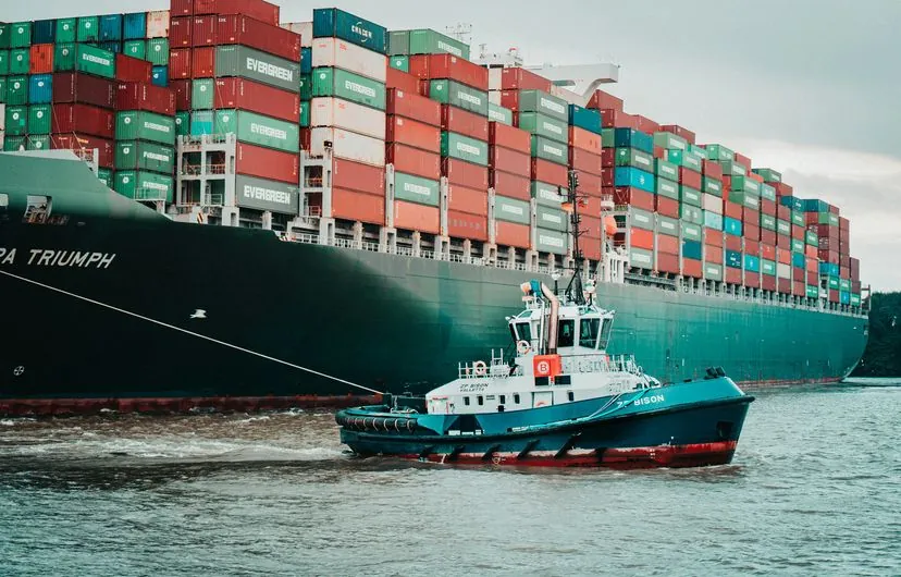 Buque portacontenedores con remolcador en el puerto
